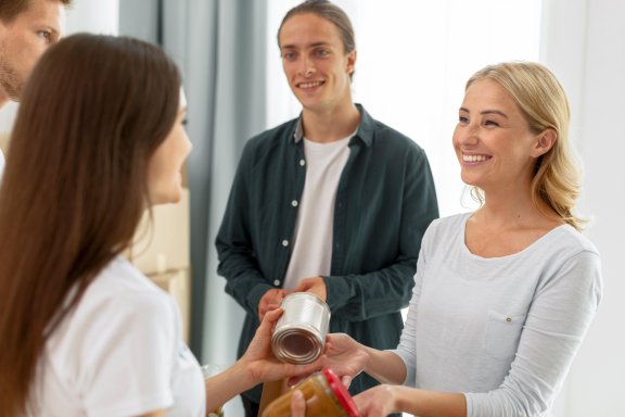 cheerful volunteers giving out food donations by freepik