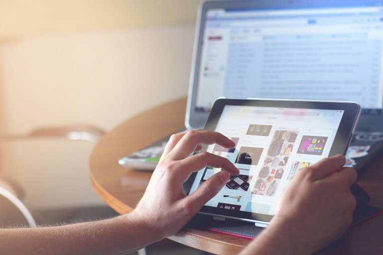 photo of someone using tablet with laptop also in view