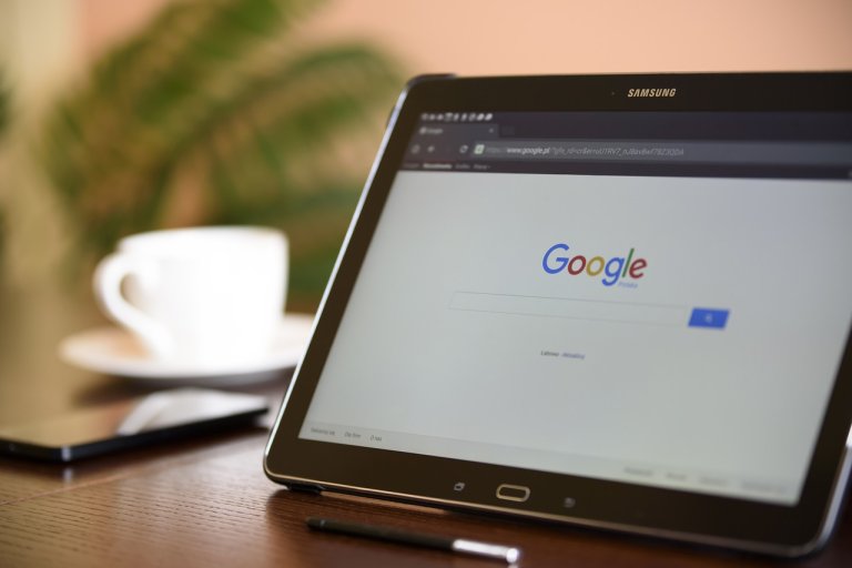 tablet open to search engine google on a desk with a coffee cup