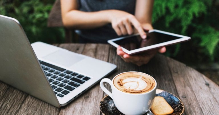 laptop vs tablet for college, tablet vs laptop for college, woman on tablet and laptop with coffee